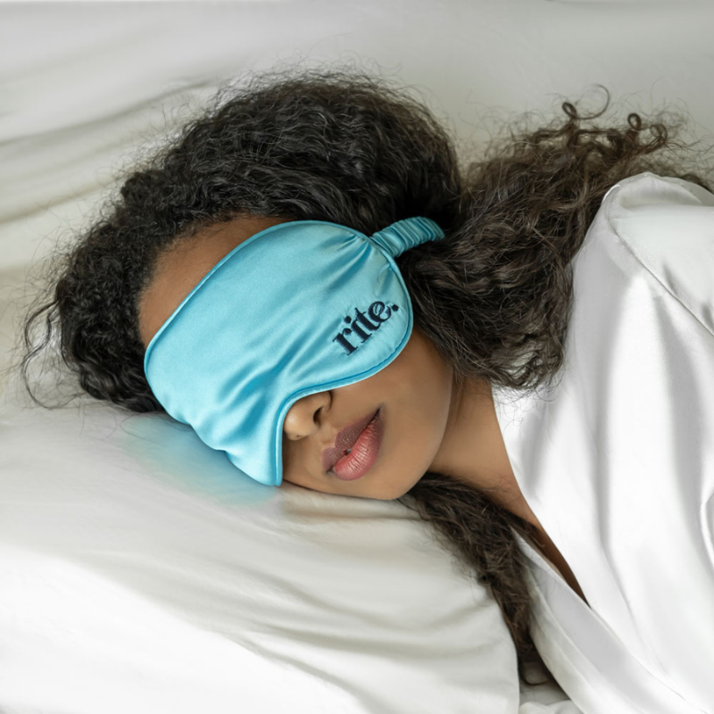 A woman peacefully sleeping with a blue eye mask on.