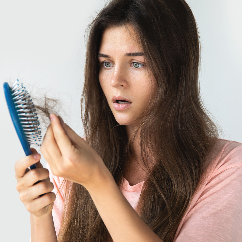 Woman combing their hair with a wide-tooth comb. Describes tips for healthy hair, including combing and exploring the role of diet.