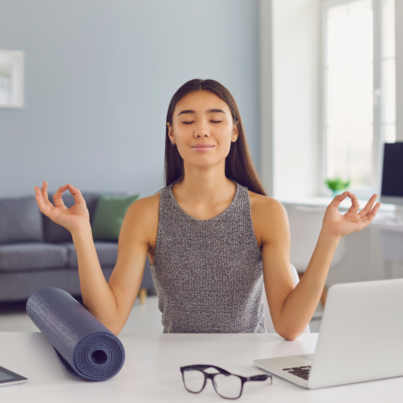 A woman meditating in front of a laptop, focusing on improving Daily Focus.