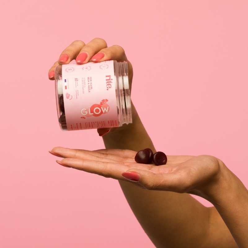 A woman holds a jar ofgummies against a pink background. GLOW gummies - The skincare you can eat!