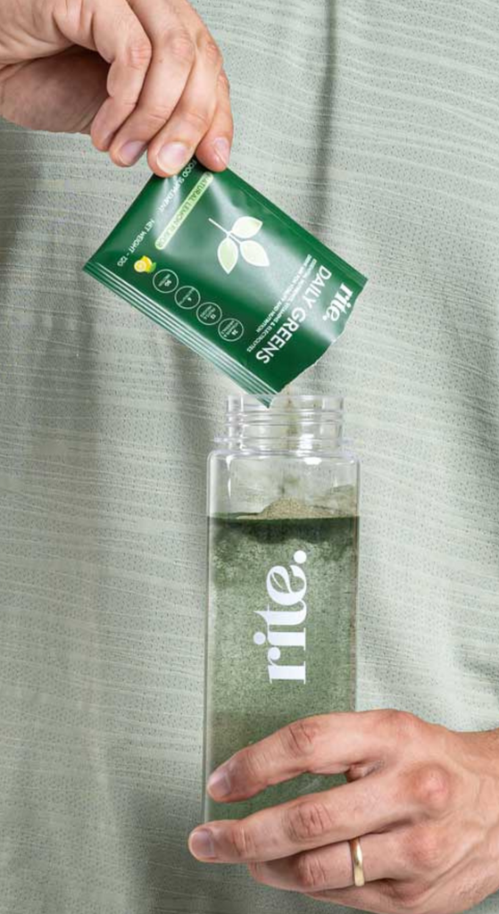 DAILY GREENS powder being poured into a water bottle for natural detox, immunity boost, and plant-based nutrition support