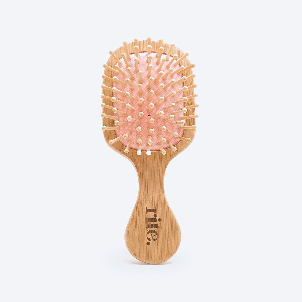 A wooden hair brush with pink bristles on a white background.