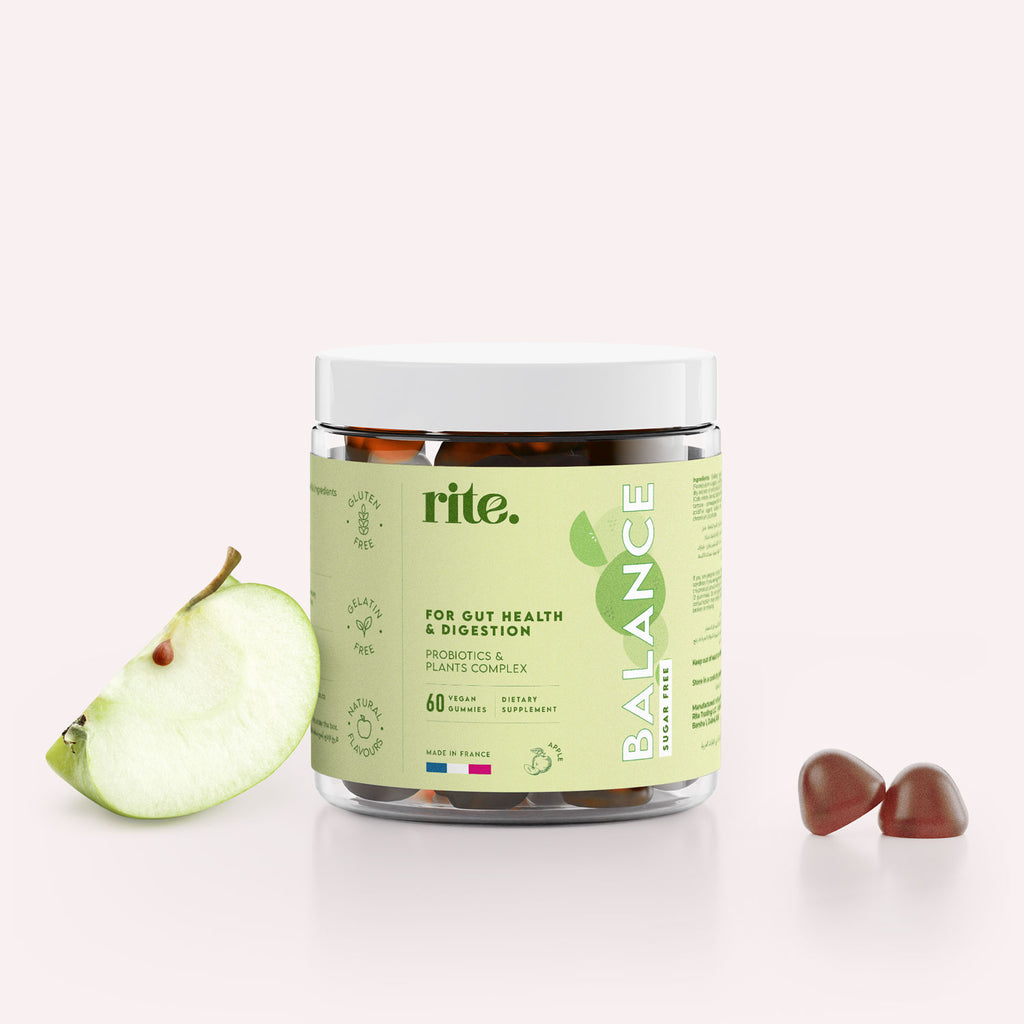 A jar of Rite BALANCE Vegan Gummies sits on a table next to a green apple. 