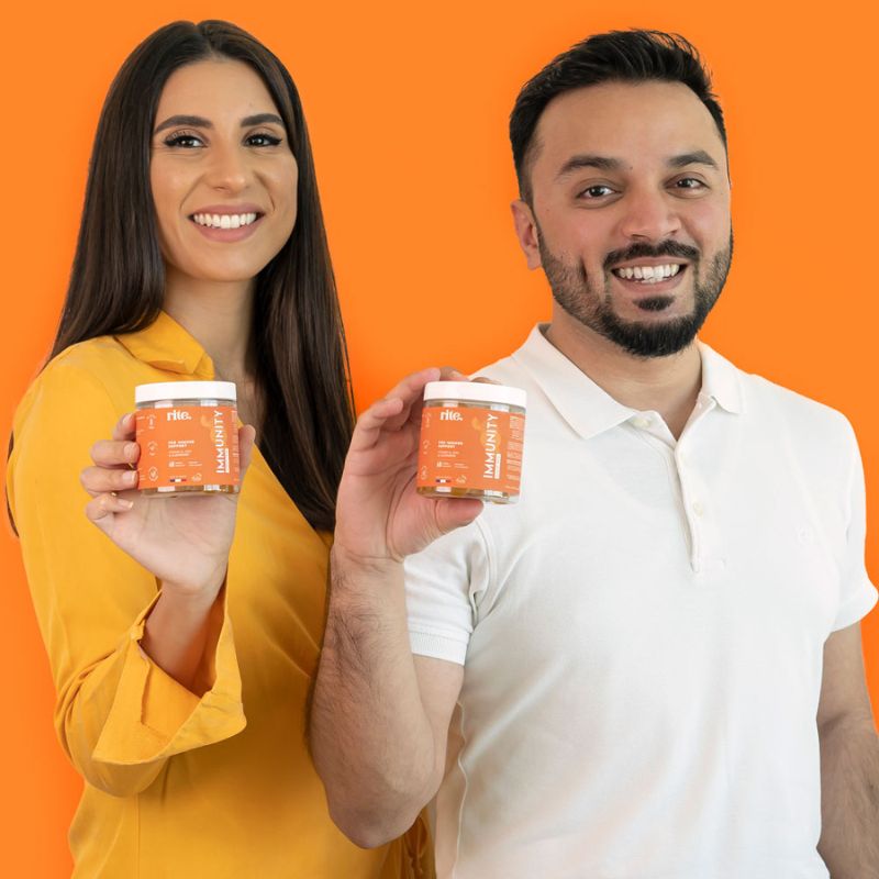 A man and woman holding up jars of vitamins labelled " Immunity gummies"