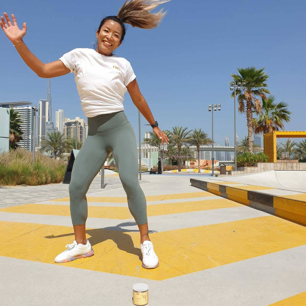 Woman wearing grey leggings shows off dance moves on a skateboard.